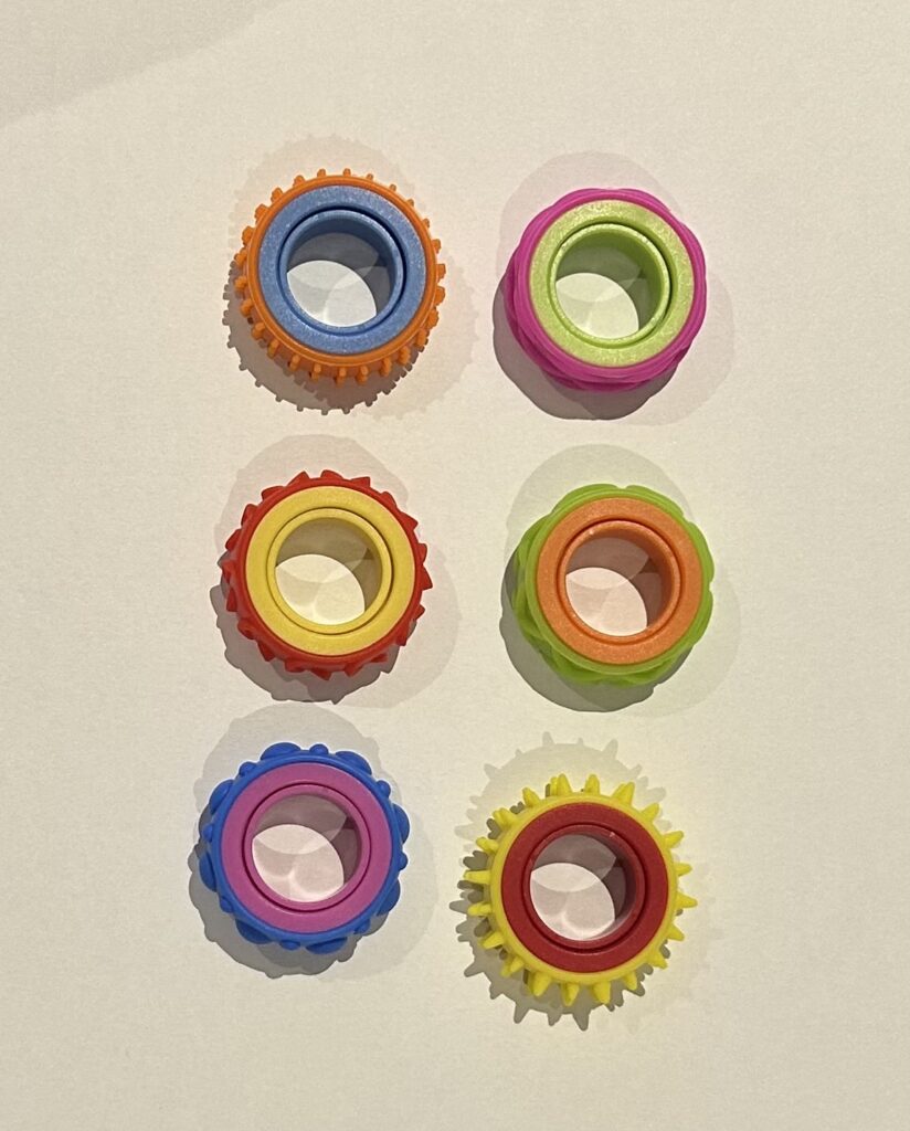 A satisfying spin in the palm of your hand. These colourful gear-style fidget rings are perfect for children and adults who need a discreet, quiet way to stay focused and regulated. Available in a range of fun colour combinations.
